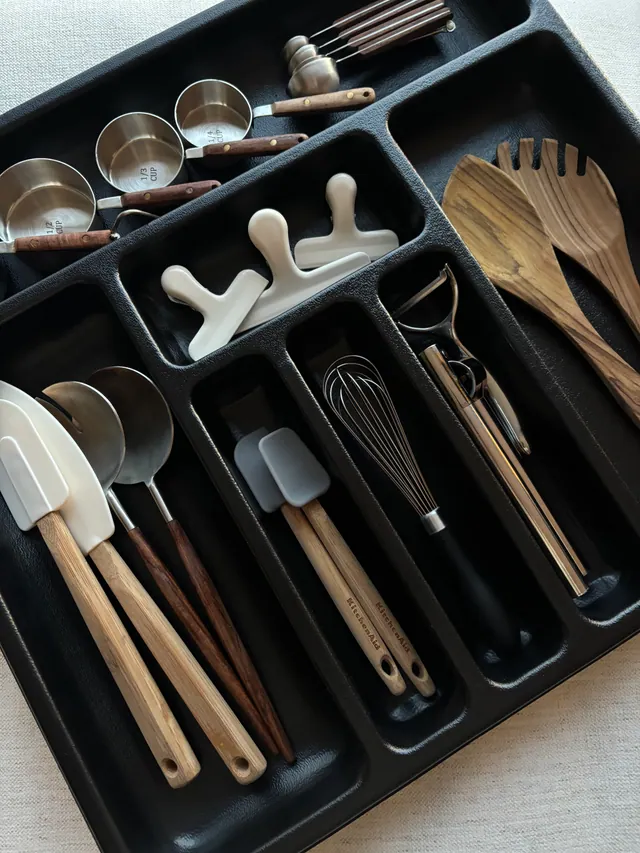 Gros plan d’un séparateur noir contenant des accessoires et des ustensiles de cuisine.